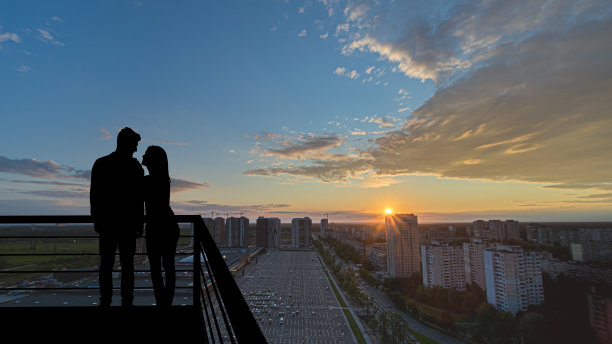 这对浪漫的情侣站在以城市为背景的阳台上图片下载