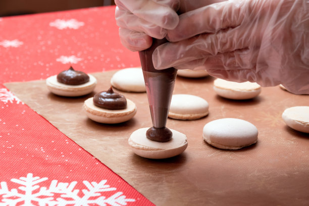 把巧克力奶油挤在一半的杏仁饼干上。制作圣诞甜点的过程。有选择性的重点。图片下载