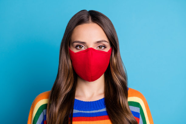 近距离的照片迷人的女人在红色医疗面具看在相机准备防止covid感染穿套头衫孤立的蓝色背景图片下载