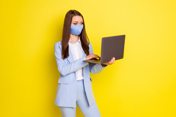照片严肃的律师老板女士工作远程covid隔离使用笔记本电脑聊天领伴侣穿蓝色夹克夹克长裤长裤医疗口罩隔离明亮的亮颜色背景图片下载