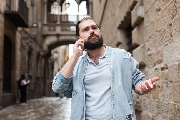一个拿着智能手机的男人在城市街道上打电话图片下载