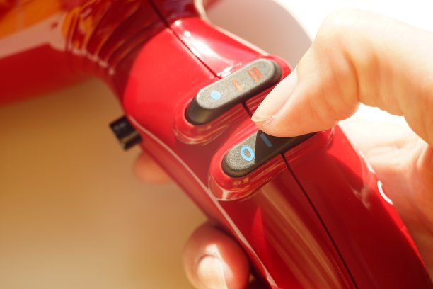 用手指触摸吹风机手柄，特写手柄有按钮图片下载