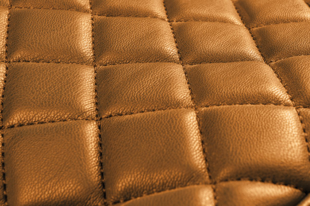 现代豪华轿车棕色皮革内饰。部分穿孔皮革汽车座椅细节。橙色穿孔皮革纹理背景。纹理，人造皮革与对角线拼接。真皮座椅图片下载