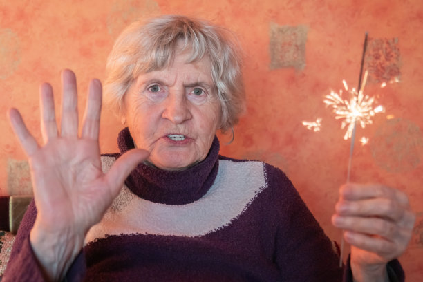 年长的女士手拿烟火祝贺圣诞图片下载