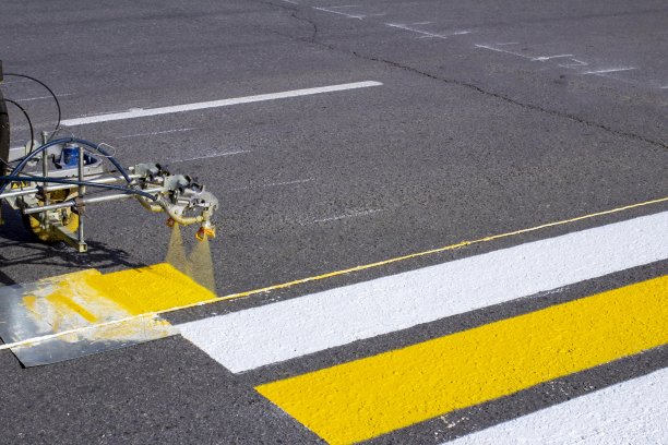 早春，一组工人在新铺的柏油路上使用自动化设备绘制人行横道图片下载