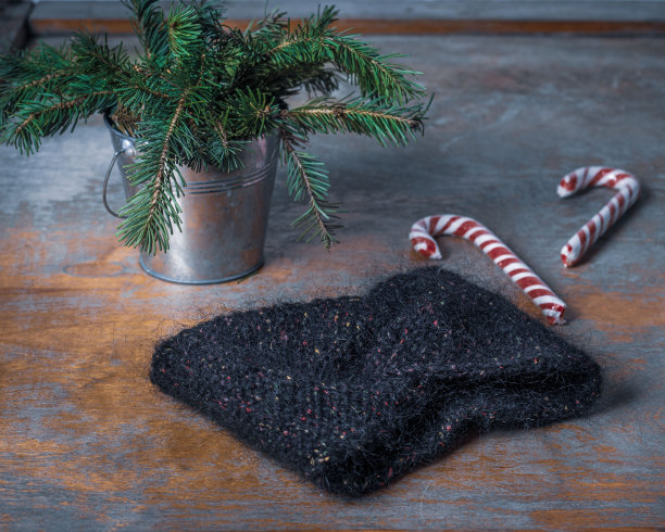 妇女用于寒冷天气的针织头巾和一个用冷杉树枝做成的桶图片下载