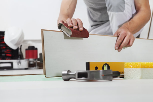 工人手动安装木材层压白地板。使用砂纸进行精密抛光。木地板房屋装修。图片下载