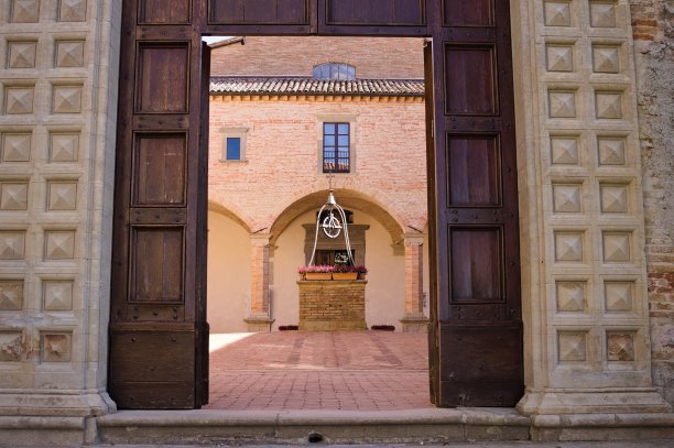 中世纪修道院入口的旧木门，院子里有一口砖井(意大利翁布里亚古比奥)图片下载