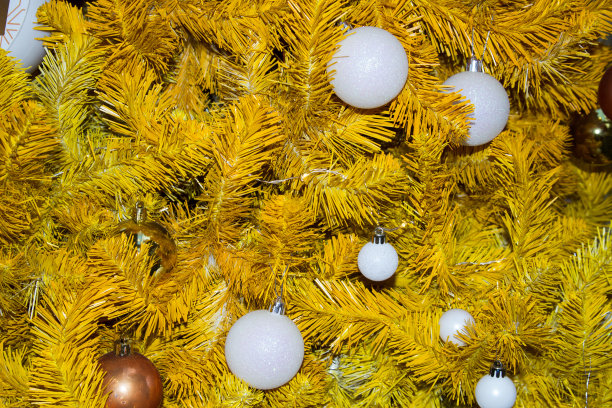 一个黄色的圣诞树和白色气球的特写。圣诞节的背景。图片下载
