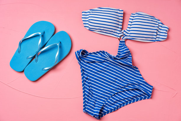 蓝色条纹的比基尼配上粉色背景的蓝色人字拖图片下载