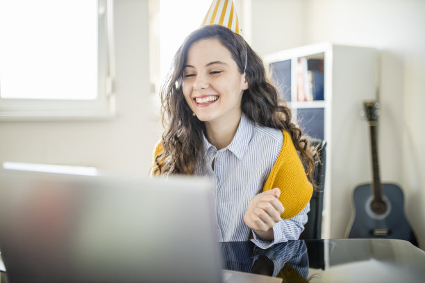 一位女士正在通过网络电话与亲戚朋友“虚拟”庆祝她的生日。她在新冠肺炎隔离期间在家。图片下载
