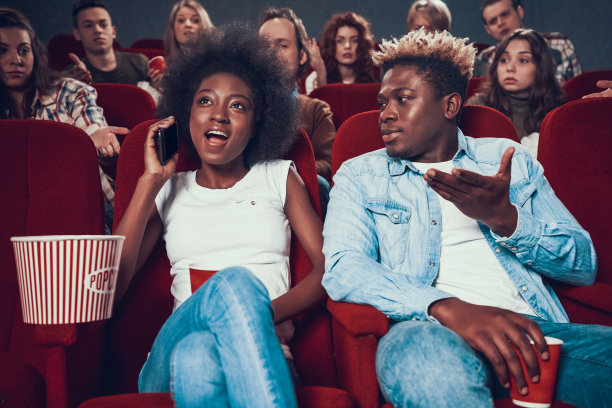 非洲裔美国妇女在看电影时大声打电话。图片下载