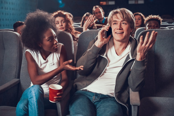 一个年轻人在电影院打电话。图片下载