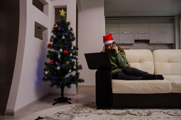 在除夕夜和新年假期，戴圣诞帽的女孩会坐在家里沙发上上网工作图片下载