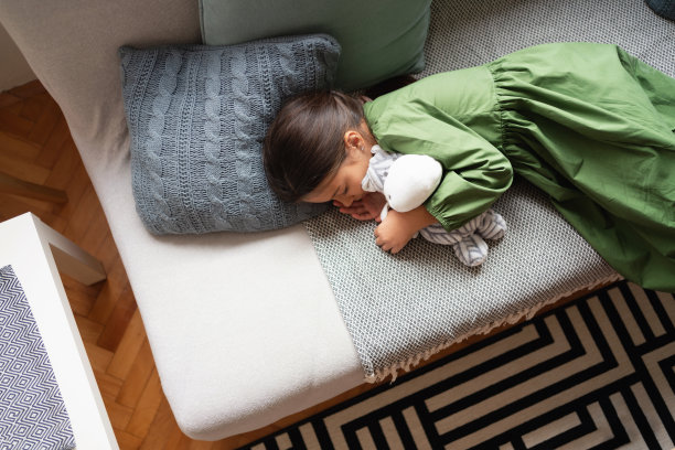 隔离期间，小女孩和她的玩具在沙发上小睡的俯视照片图片下载