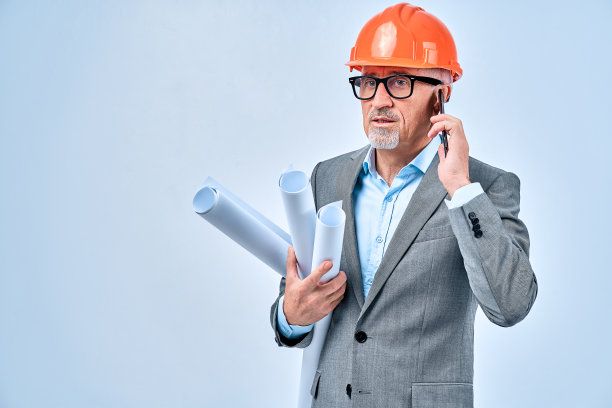 严肃的建筑师，戴着眼镜，在工作室拿着设计图图片下载