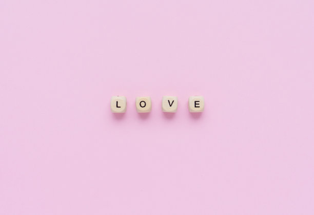 粉彩背景上刻有“爱”字样的木制立方体。情人节或婚礼的概念。平躺，俯视图。爱的概念。图片下载