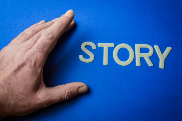 人的手旁边用塑料字母在蓝纸背景上写故事，概念图片下载