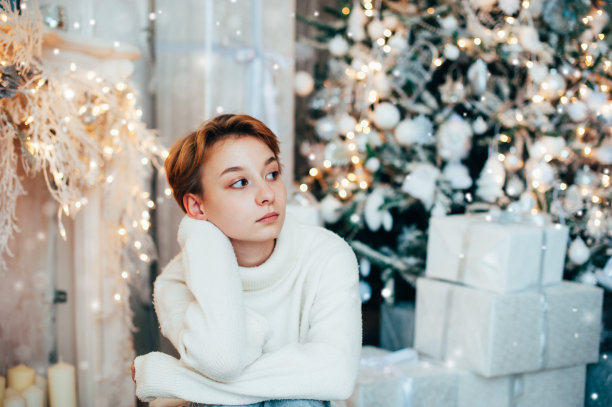 一个美丽的十几岁的女孩穿着舒适的毛衣等待圣诞节和梦想图片下载