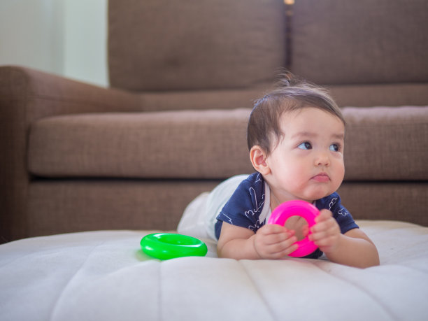 胖乎乎的婴儿，无聊的脸躺在室内的地板上。图片下载