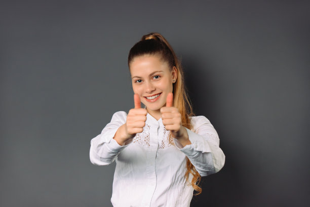 女商人庆祝成功并在镜头上展示自己的班级。灰色的背景。图片下载