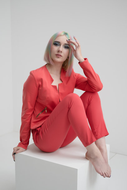 一个年轻美丽的金发女孩的肖像染了头发。红色夹克西装上的。工作室拍摄在一个白色的背景。图片下载