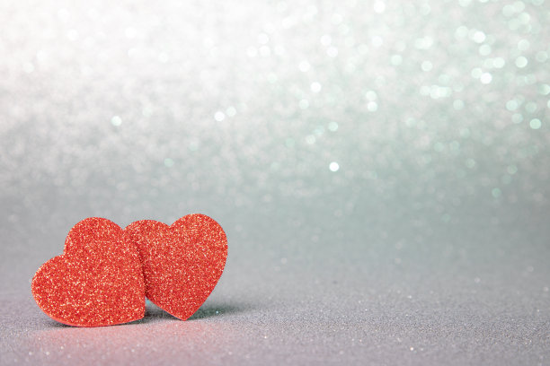 两颗闪闪发光的红心在银色的闪闪发光的背景上图片下载