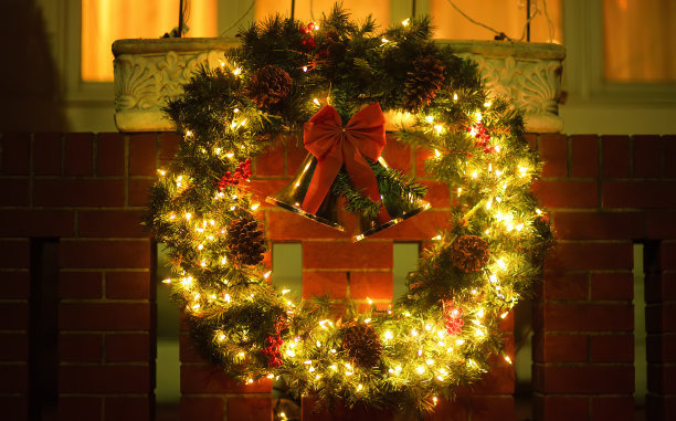 前门上挂着红铃铛的圣诞绿花环。为了迎接圣诞节和新年的到来，房子的大门被装饰一新。图片下载