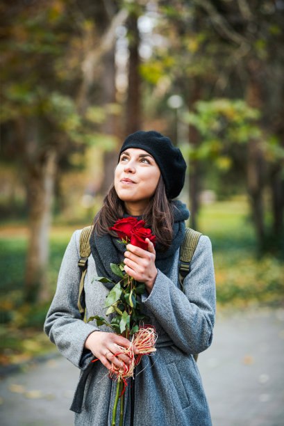 迷人的年轻白种女人捧着一束新鲜的红玫瑰股票照片。情人节/约会/爱情概念。图片下载