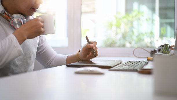 平面设计师在电脑上编辑一些图片，在他的家庭办公室喝咖啡。图片下载