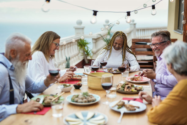 快乐的多种族高级朋友享受晚餐在家里的露台-食物和饮料图片下载