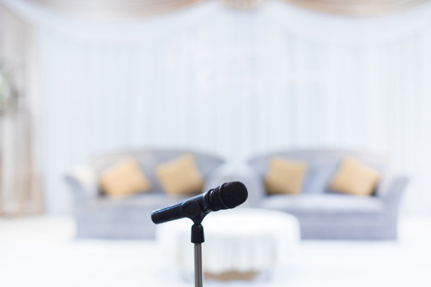 在音乐厅或会议室的麦克风柔和和模糊风格的背景。麦克风上方是会场或会议室背景的抽象模糊照片。图片下载