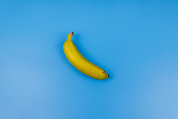 淡蓝色背景上的黄色香蕉。俯视图，平面铺设，最小的设计图片下载