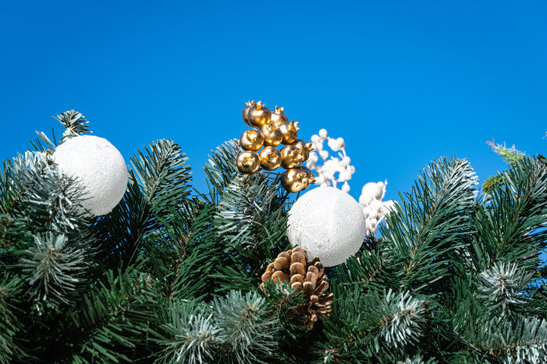 美丽的圣诞白球在绿色的人造树枝上，映衬着蓝天。特写镜头。有选择性的重点。圣诞装饰品。新年和圣诞节的魔术主题。图片下载