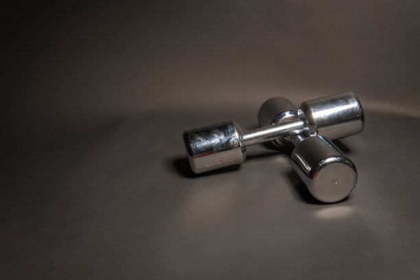 健身哑铃，在黑色背景下闪耀着金属色图片下载