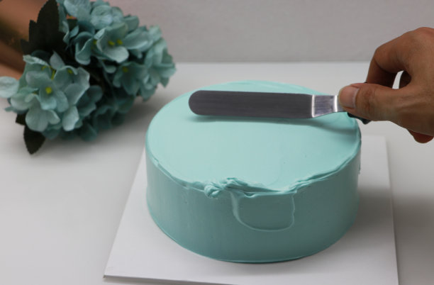 用设备手刮绿色奶油。来装饰绿色的磅饼图片下载