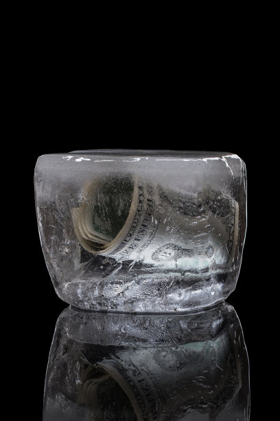 钱冻结在冰里。冻结存款的概念。外国银行账户。孤立在黑色背景上。图片下载