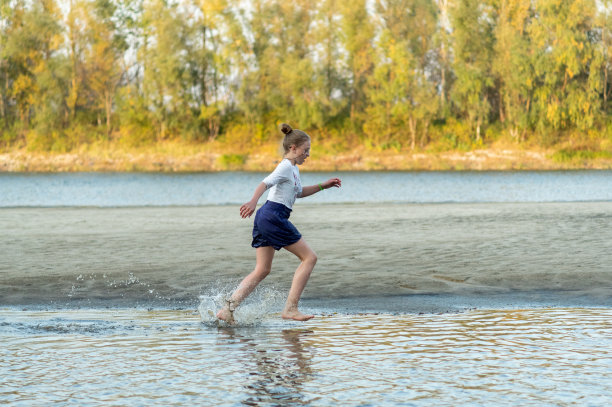 一个女孩在水上奔跑。女孩泼水。河。图片下载