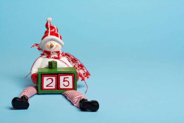 一个雪人拿着一个由两个立方体组成的数字25的盒子。今天是12月25日。今天是圣诞节。这是一年中最美的时光!图片下载