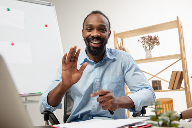 在线英语课程在家。微笑的男人在客厅里远程教学生图片下载