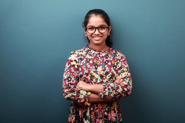 一个快乐的年轻女孩站在蓝色的墙背景图片下载