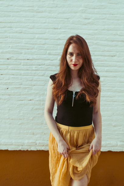 年轻温柔的红头发年轻女孩的肖像与健康的雀斑皮肤穿着黑色的顶摆出严肃或沉思的表情。白种人女性模特与姜头发摆姿势户外。图片下载