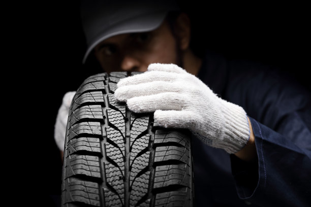 汽车修理工在黑色背景下检查汽车轮胎图片下载
