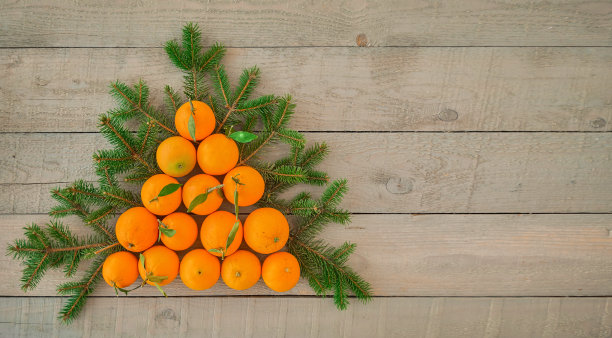 一棵圣诞树的顶部视图由新鲜的橙子和圣诞树的树枝在一个黑色的木制背景与复制空间。为节日准备一棵圣诞树或一张明信片图片下载