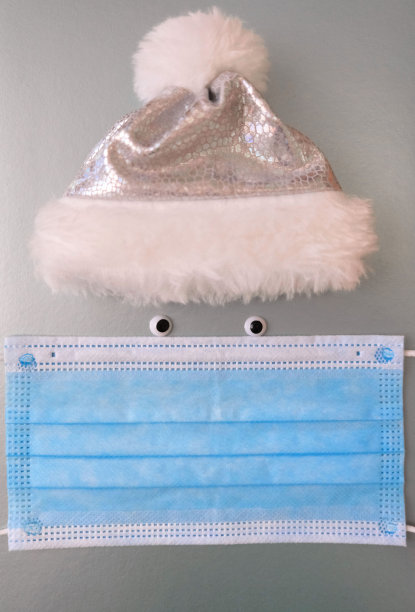 由圣诞老人帽、眼睛和医用面具制成的脸。有趣又安全的圣诞假期。本空间图片下载