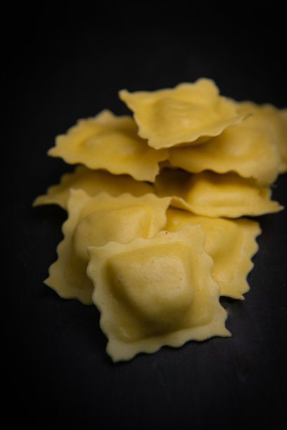 美味的生意大利饺子配上面粉和菠菜，深色背景，意大利饺子的制作过程图片下载