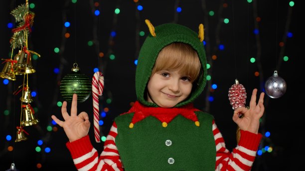 金发少年孩子孩子女孩在圣诞精灵圣诞老人助手服装表演gok手势，好标志图片下载