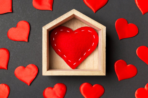 近距离的红心在一个木制的房子装饰着小的心在彩色的背景。情人节。家温馨的家概念图片下载