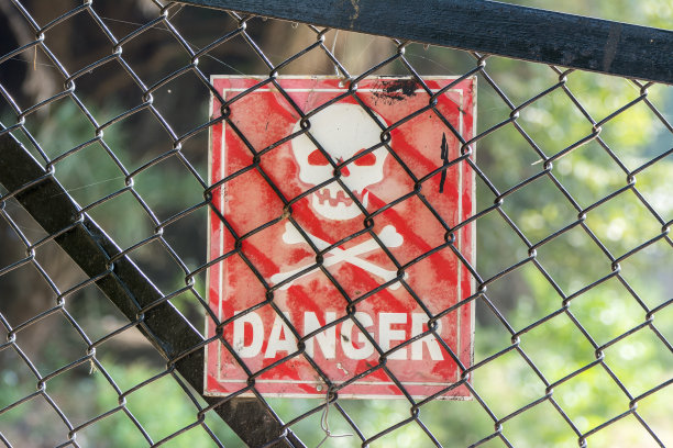 十字骨和头盖骨挂在铁丝网围栏后是危险的标志图片下载