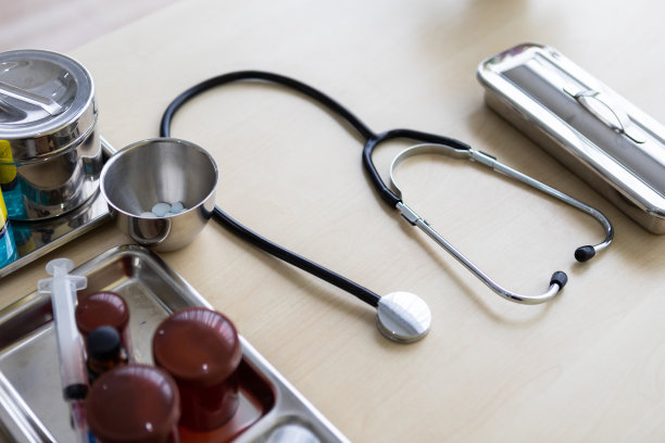 听诊器，小瓶，注射器和医疗瓶不同的药物在手术托盘与医疗设备在木桌背景图片下载